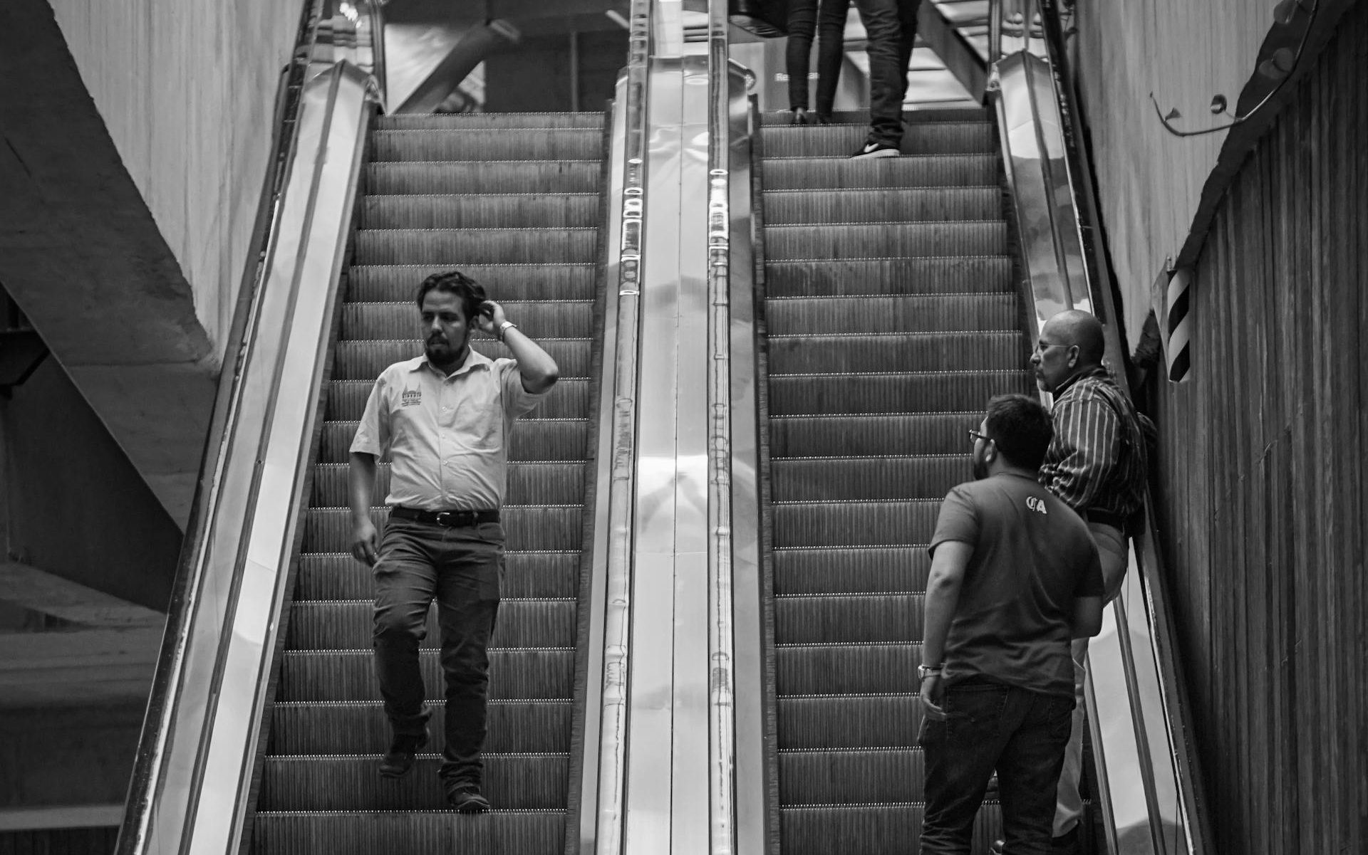 Grayscale Photography of People Riding Escalators